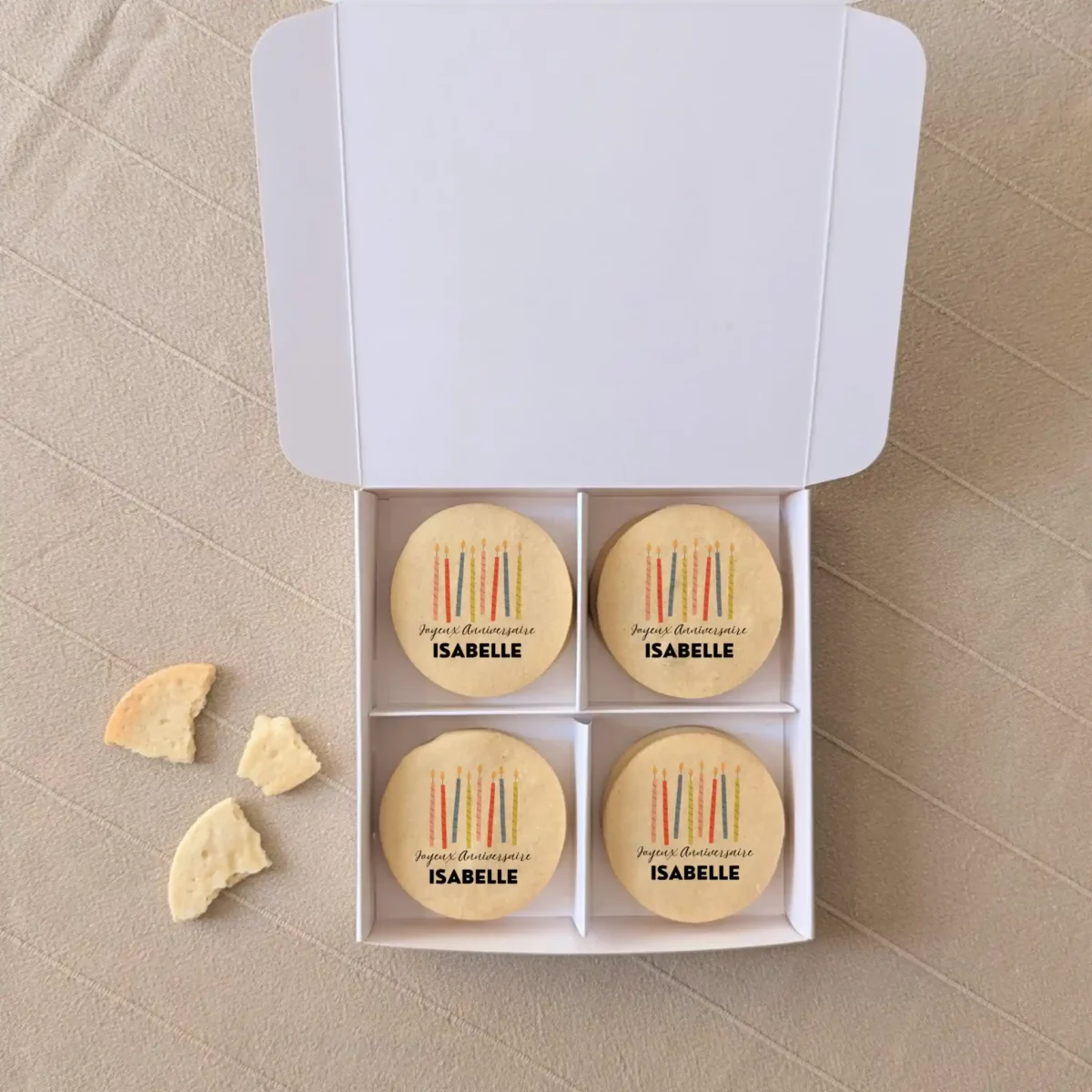 Coffret gourmand de biscuits personnalisés – idée cadeau d’anniversaire original Coffret blanc avec quatre biscuits sablés personnalisés “Joyeux anniversaire Isabelle” imprimés en couleurs, cadeau gourmand original.